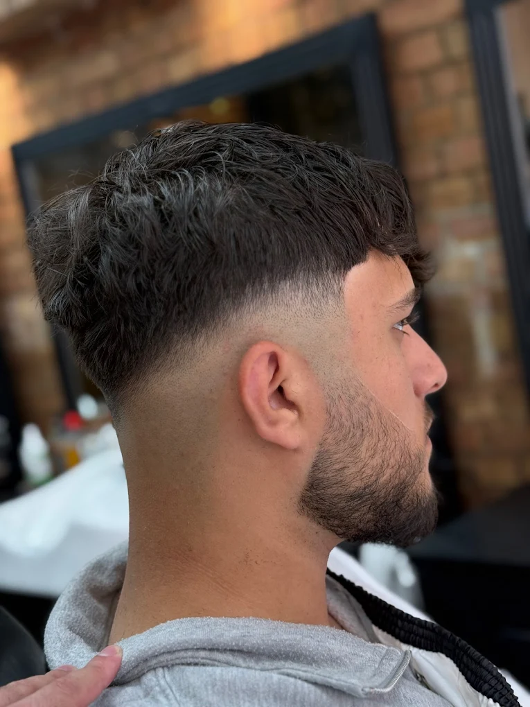 Sharp fade haircut with clean beard line at The Antique Barbers.