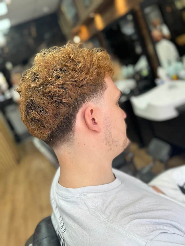 Curly textured haircut with a clean fade at The Antique Barbers.